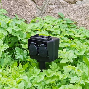 schwarze Gartensteckdose 4fach mit 3 Meter Kabel in der Wiese postioniert